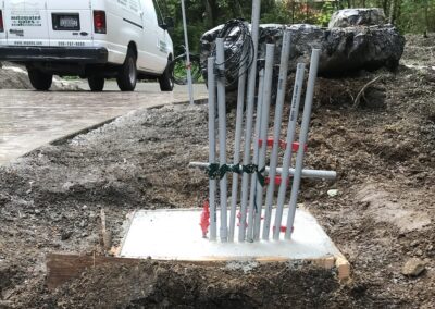 Newly Poured Foundation For A Fence Pillar With Visible Electrical Conduits